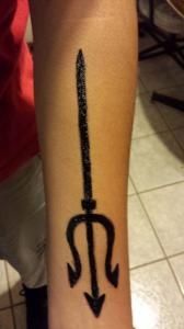 A person has a tattoo of a trident on their arm.