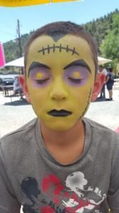 A young boy with his face painted like frankenstein