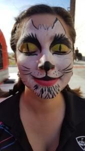 A woman with her face painted like a cat with yellow eyes.
