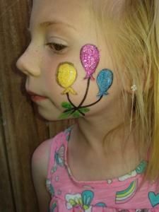 A little girl with balloons painted on her face.