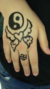 A person has a tattoo of a yin yang symbol on their hand.