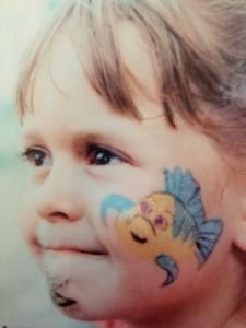 A little girl has a fish painted on her face