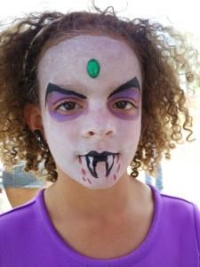 A young girl with her face painted like a vampire.