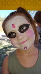 A little girl with her face painted like a doll
