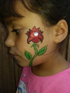 A little girl has a flower painted on her face.