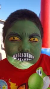 A young boy with his face painted like the hulk