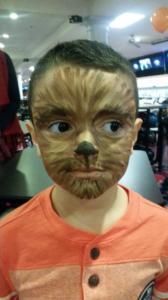 A young boy with his face painted like a werewolf.