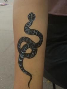 A person has a tattoo of a snake on their arm