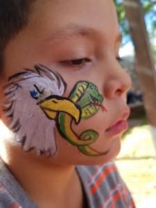 A young boy has an eagle and snake painted on his face