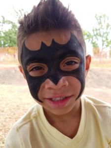 A young boy with his face painted like batman