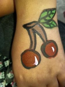 A child has two cherries painted on their hand