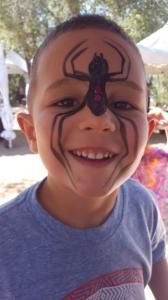 A young boy with a spider painted on his face.