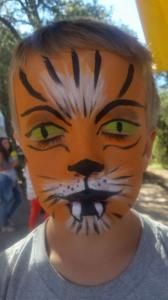 A young boy has his face painted like a tiger