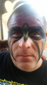 A man with face paint on his face is wearing a black shirt.