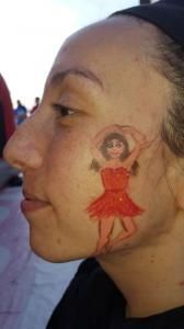 A woman with a drawing of a ballerina on her face.