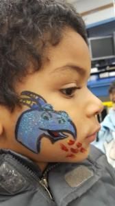 A young boy has a blue bird painted on his face