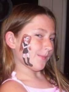 A little girl with a doll painted on her face