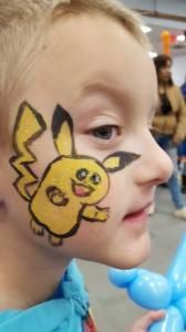 A young boy has a pikachu face painted on his face.