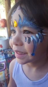 A little girl with her face painted like a unicorn.