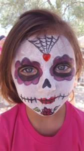 A little girl with her face painted like a sugar skull.