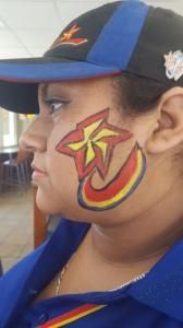 A woman wearing a baseball cap has a star painted on her face.