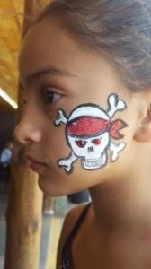 A young girl has a pirate skull painted on her face.