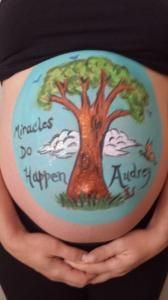 A pregnant woman has a tree painted on her belly.