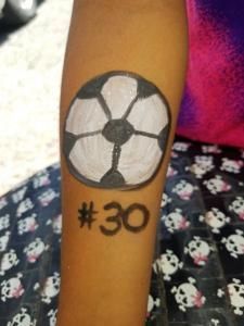 A person has a soccer ball painted on their arm