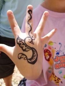 A child 's hand has a tattoo of a snake on it