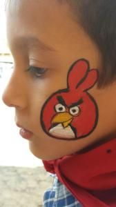 A young boy has an angry bird painted on his face.