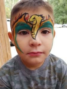 A young boy has a dragon painted on his face.