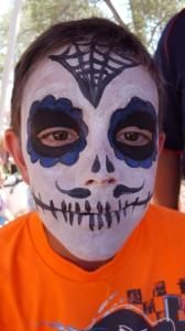 A young boy with his face painted in the shape of a skull.