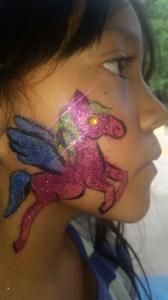 A young girl has a unicorn painted on her face.
