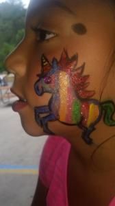 A little girl has a unicorn painted on her face.