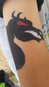 A person has a black dragon tattoo on their arm.