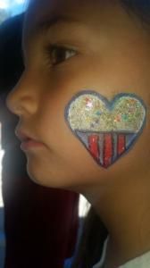 A young girl has a heart painted on her face.
