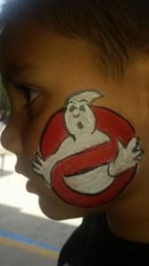 A young boy has a ghostbusters logo painted on his face.