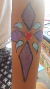 A person has a stained glass design painted on their arm.