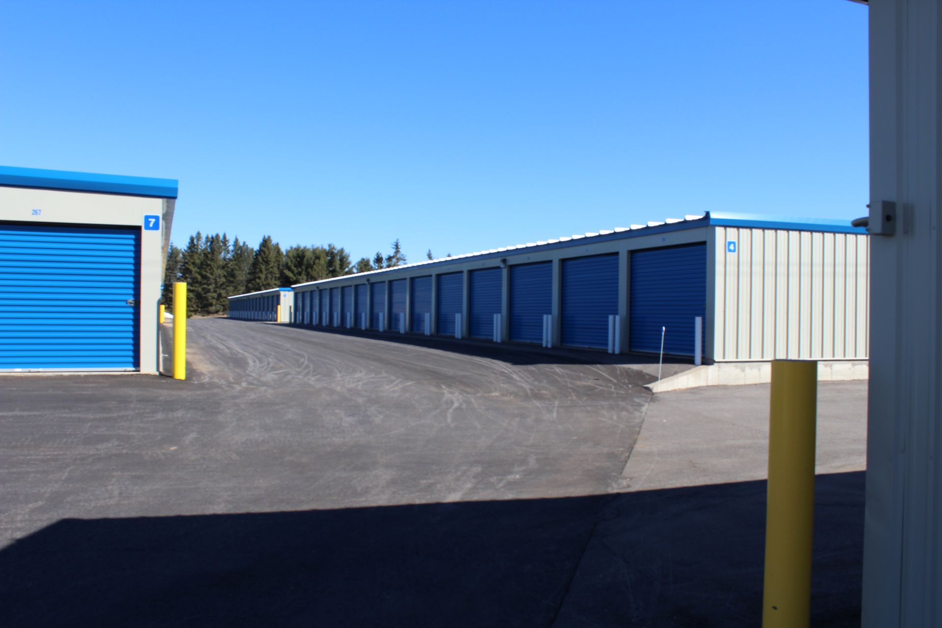 A row of storage units with blue doors are lined up in a parking lot