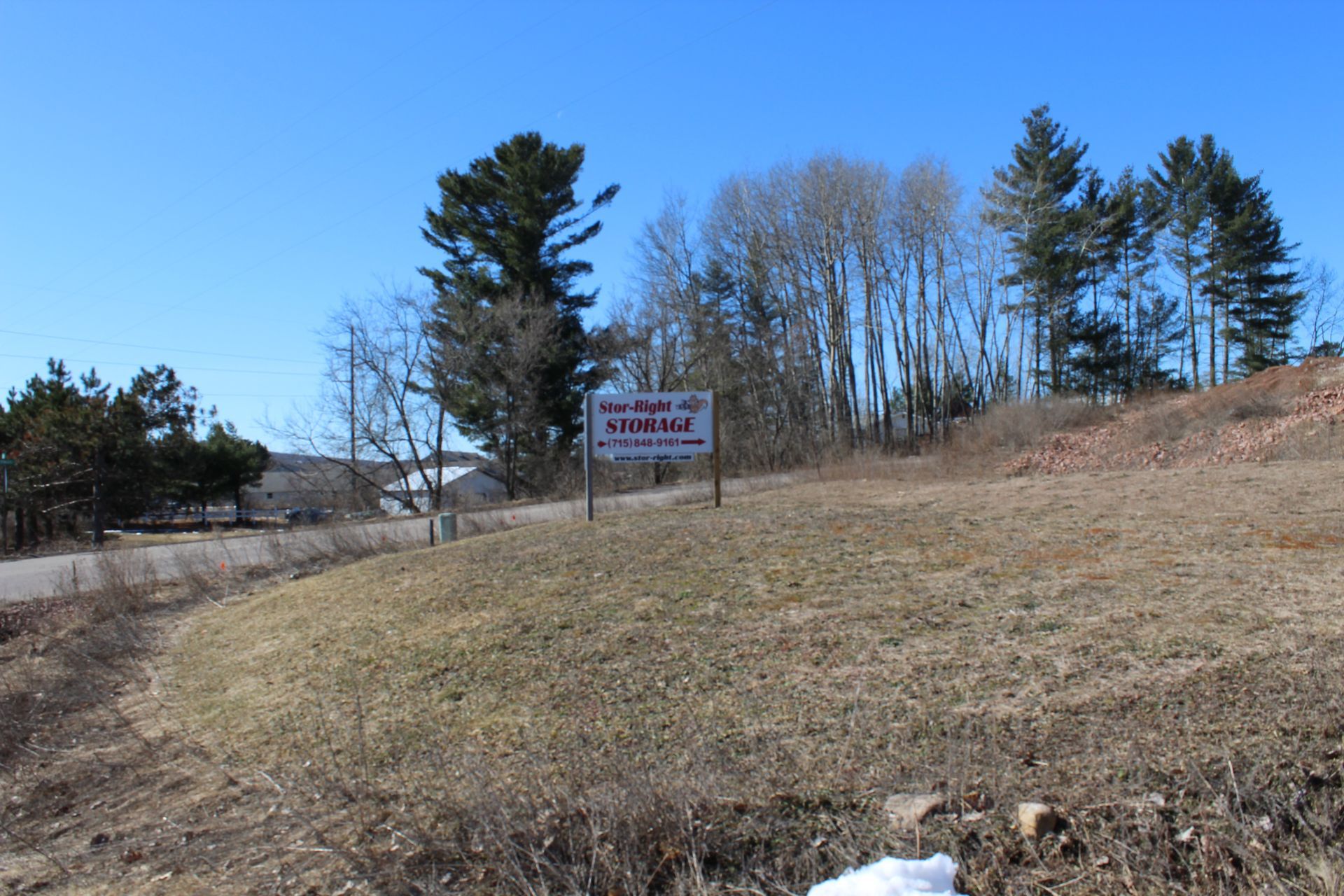 A storage sign in the middle of a field with some trees behind