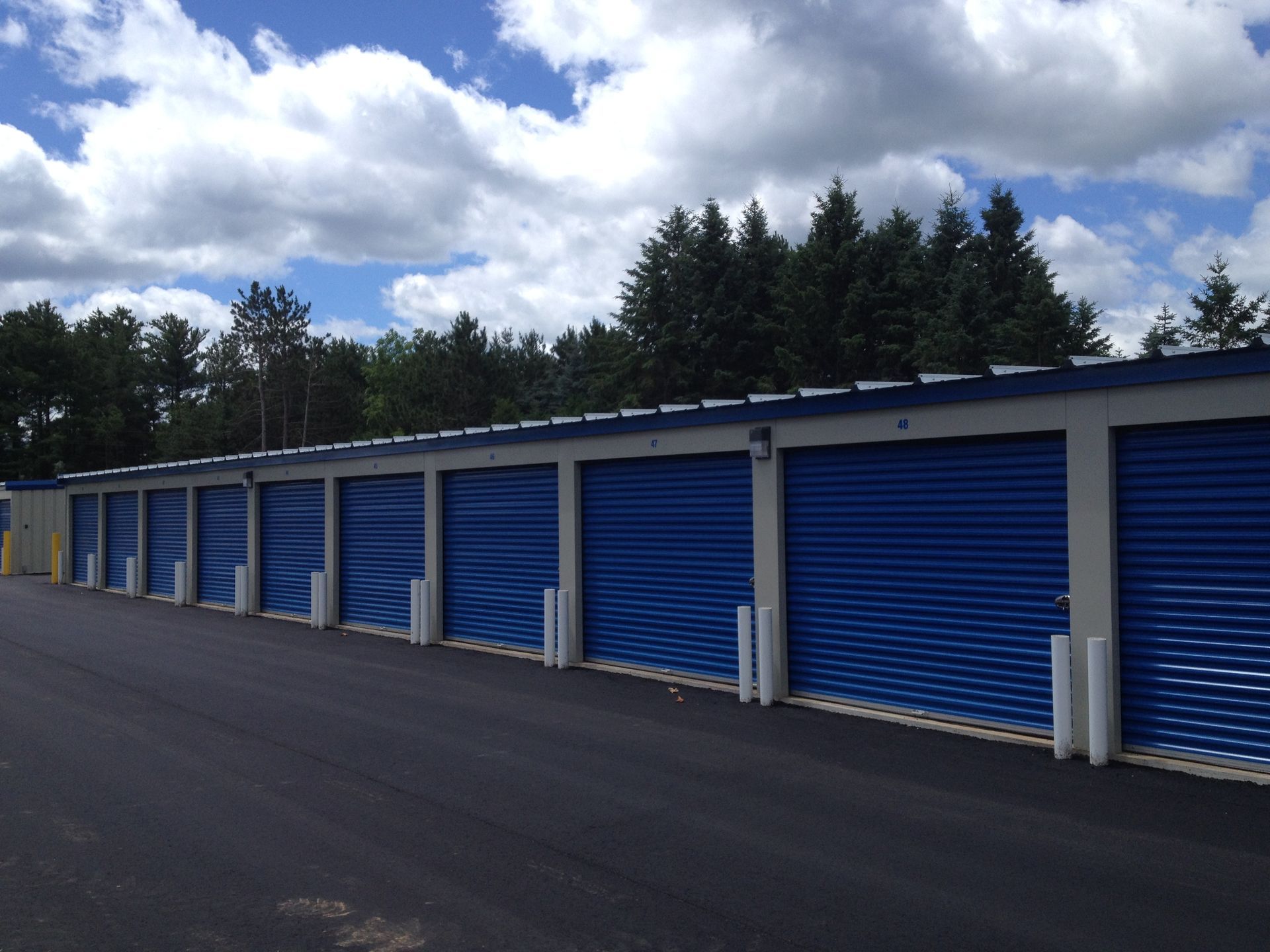 A row of blue garage doors with trees in the background