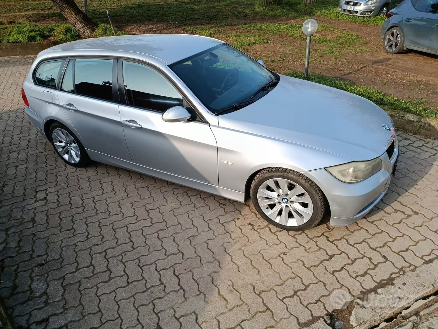 Una station wagon argentata parcheggiata su un vialetto di mattoni, vista dall'alto.