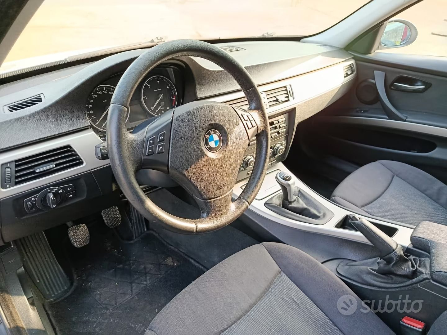 Interno di un'auto BMW, che mostra il volante, il cruscotto, i sedili e la console centrale.