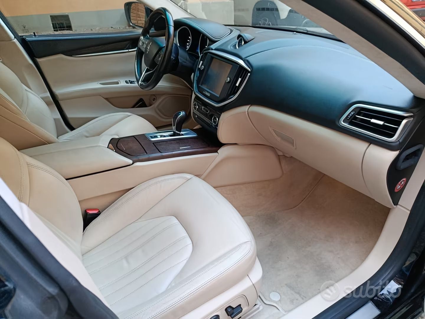 Interni di lusso per auto con sedili in pelle beige, cruscotto e console centrale neri.