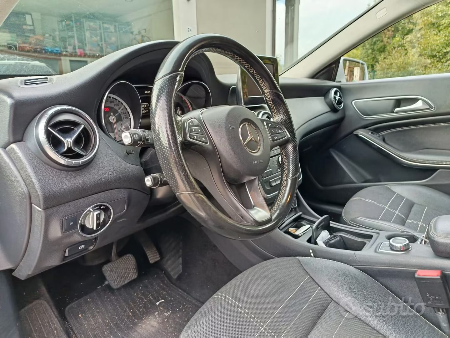 Interni di un'auto di lusso con sedili, volante e cruscotto in pelle nera, visti dal lato del guidatore.