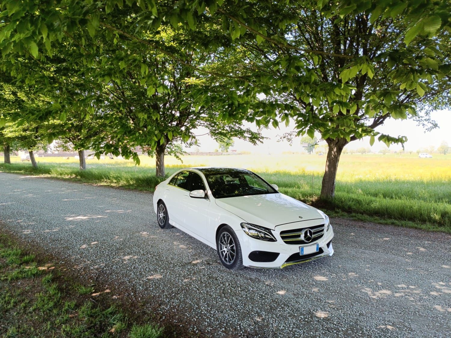 Piazza del paese lastricata di ciottoli con due auto nere, edifici storici in pietra e il campanile di una chiesa al crepuscolo