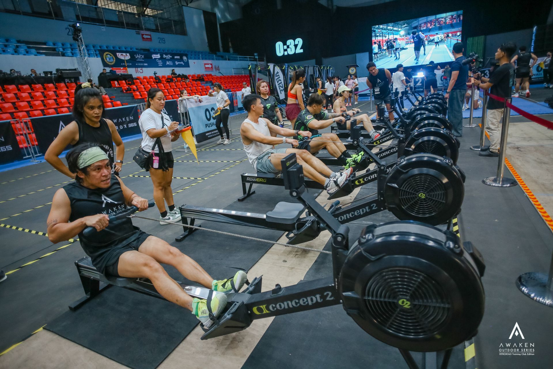 A group of people rowing on Concept2 machines during an indoor fitness competition.