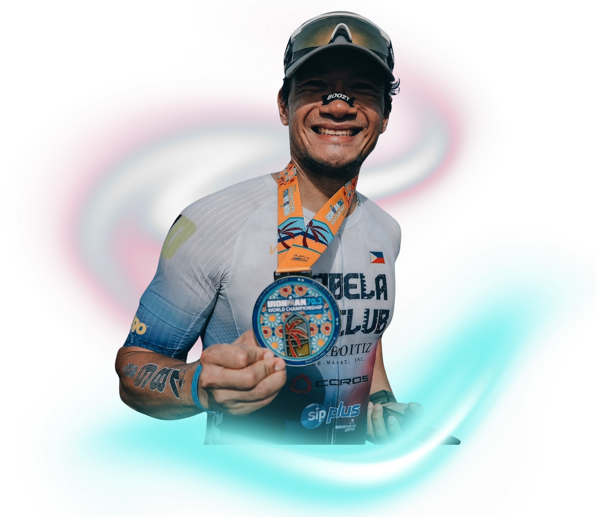 A person wearing a sports jersey and cap smiles while holding up a colorful circular medal against a blurry background.