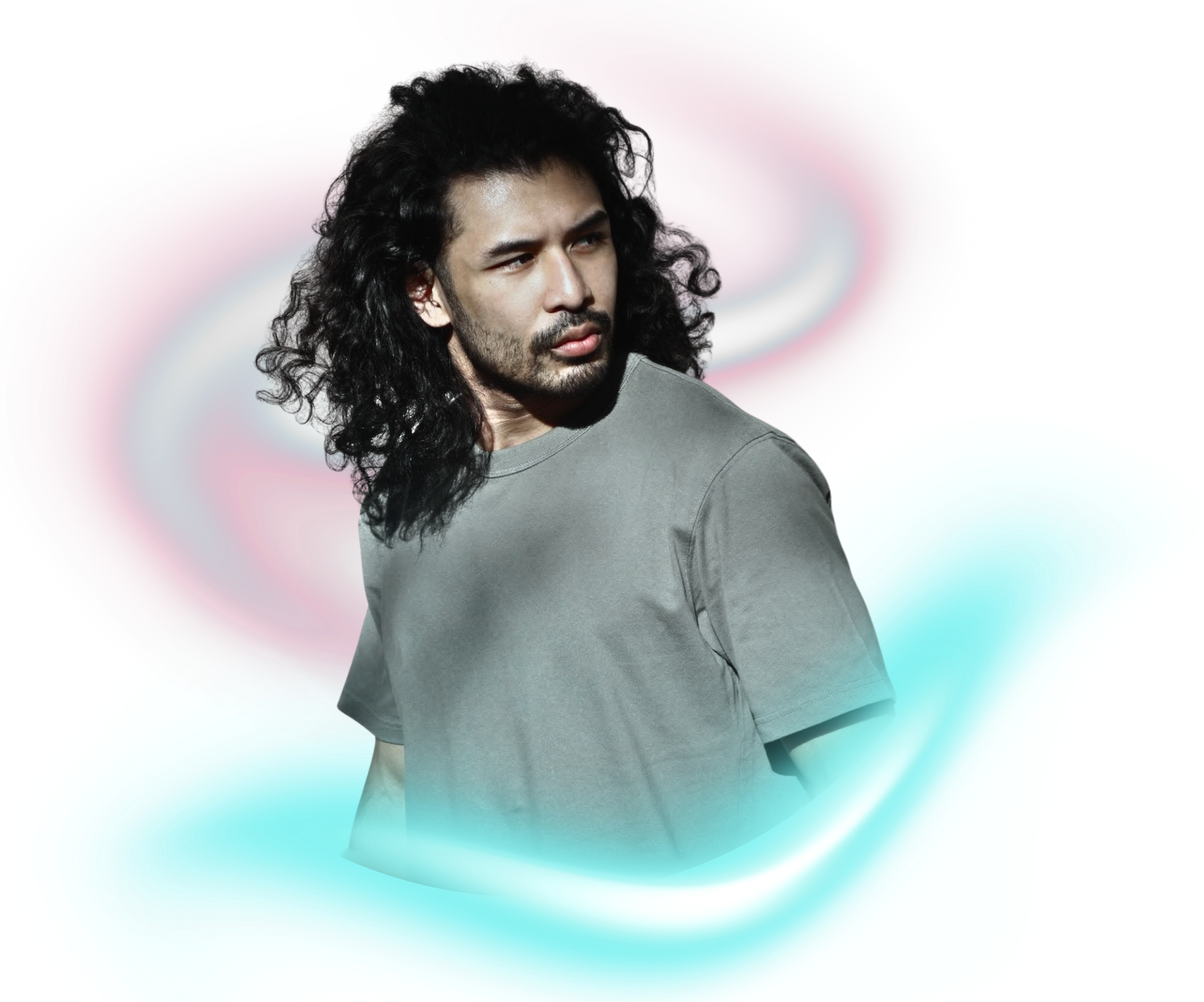 A person with long, dark, curly hair wearing a gray t-shirt, posed against a background of soft, glowing light swirls.