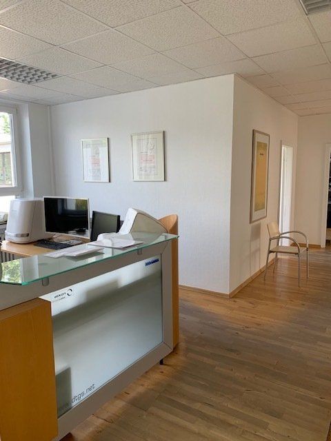 Ein Wartezimmer mit Schreibtisch, Stühlen und einem Computer